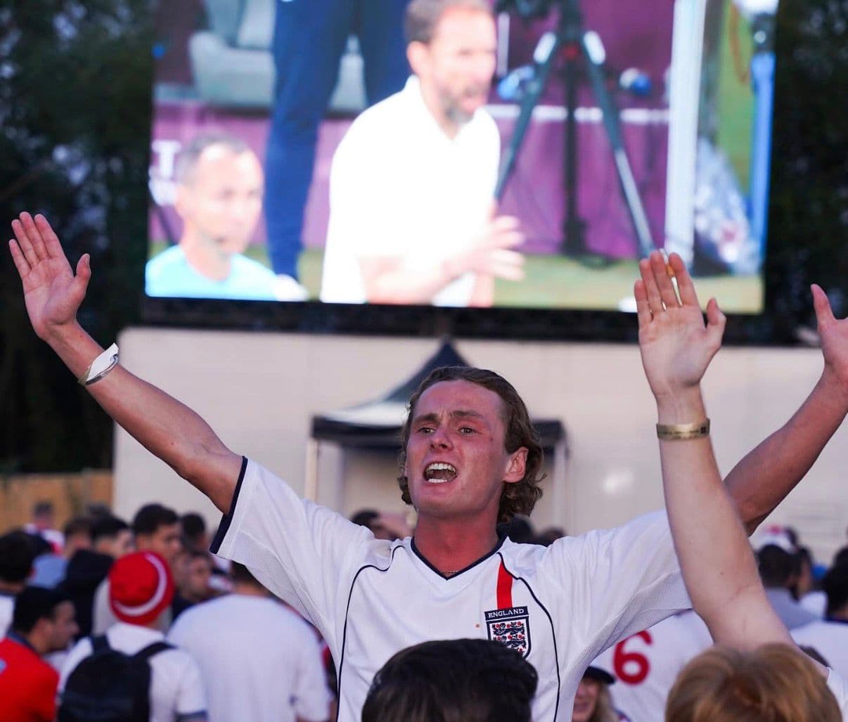 England fan celebrating in front of giant LED screen at FanZone UK