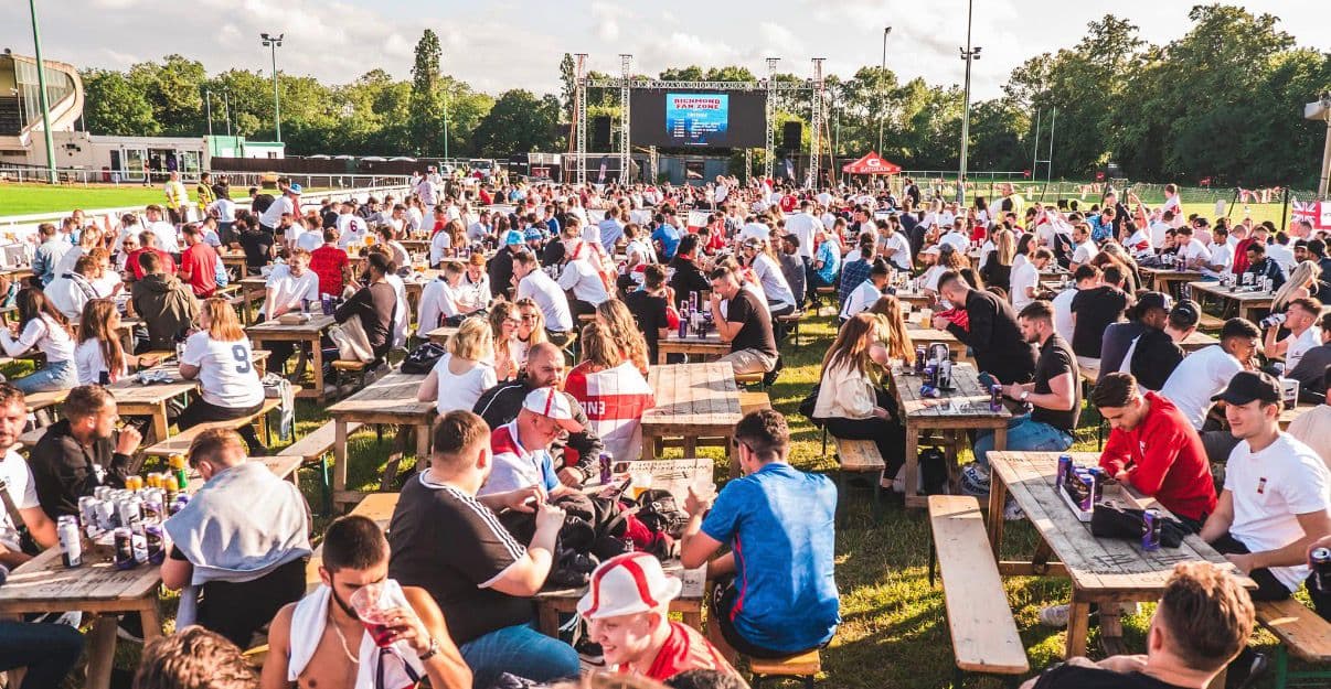 Outdoor viewing area with benches and big screen at FanZone UK
